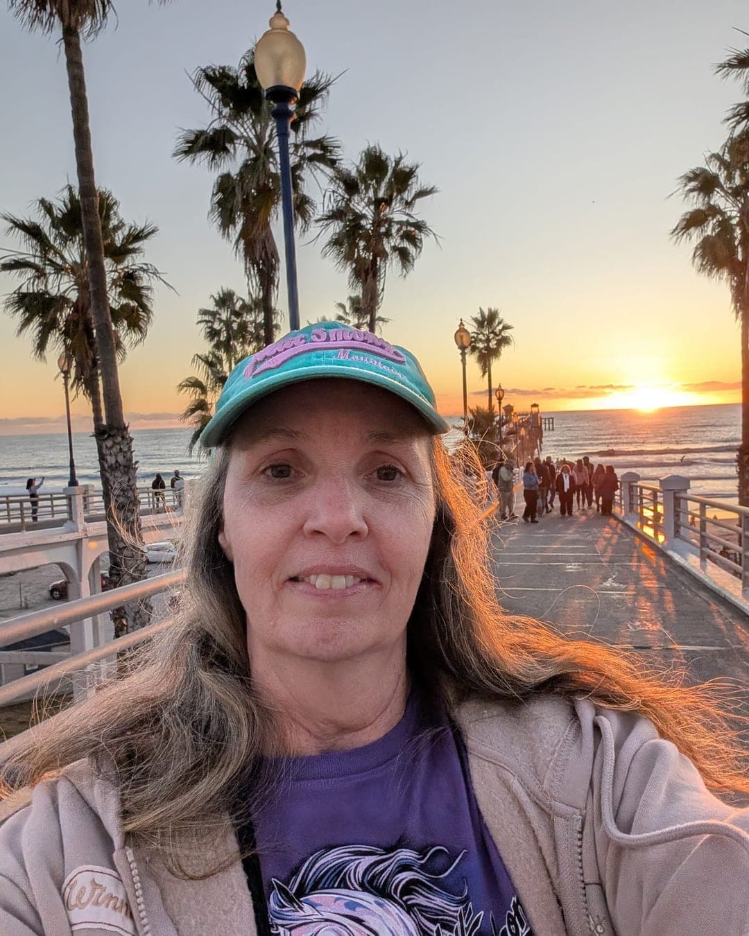 Cindy Strickland smiling on a palm-lined pier at sunset
